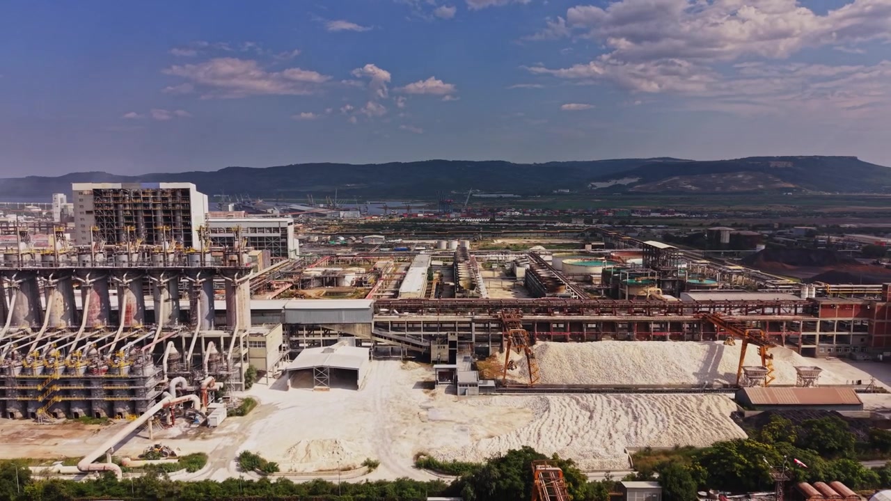 Sito industriale con macchinari e serbatoi vicino a un fiume di giorno.