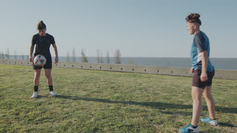 young female soccer players training with ball outdoors