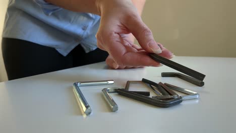 Woman-picking-up-hex-key,-multiple-allen-keys,-close-up