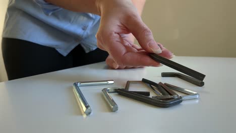 una mujer recogiendo una llave hexagonal, varias llaves allen, de cerca.