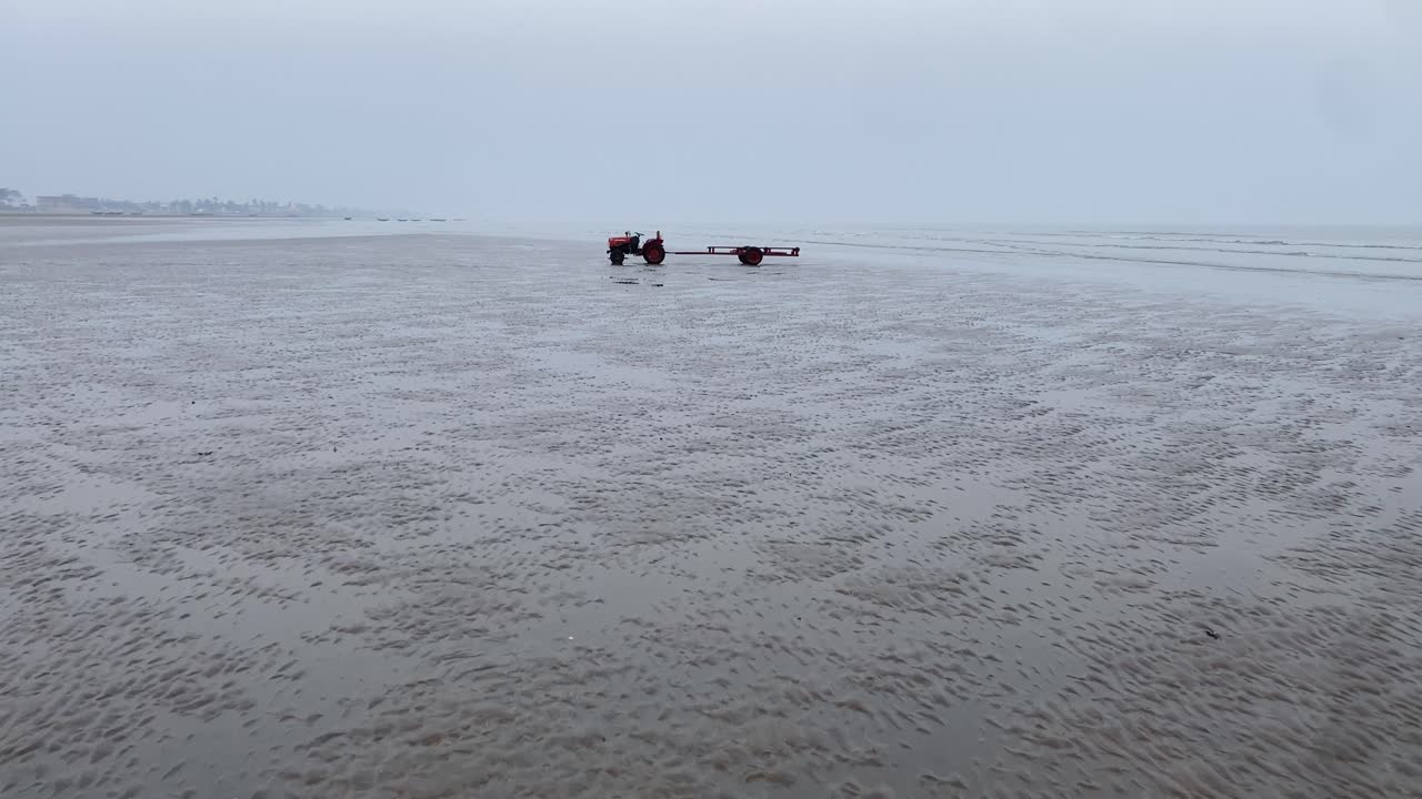 겨울철 저녁에 모래를 싣고 홀로 서 있는 트랙터가 있는 초현실적인 빈 바다 해변의 영화 같은 김블 포워드 샷