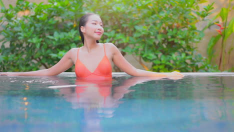 portrait of asian woman relaxing inside swimming pool of a luxury tropical hotel in bali