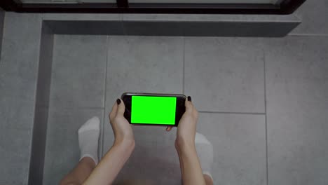 vrouw zit op een toilet met haar mobiele telefoon
