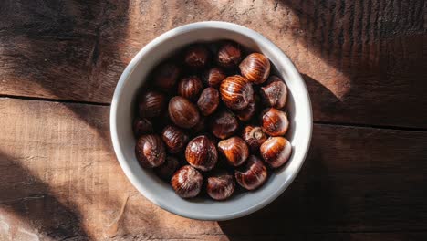 Bowl-of-Shiny-Brown-Chestnuts-on-Wooden-Table