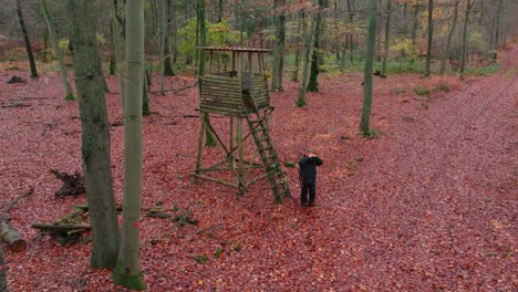 A-hunter-in-thick-winter-clothing-stands-in-front-of-a-hunting-stand