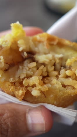savor the crispy texture of a papa rellena in this vertical video close-up. the golden-brown crust and rich potato filling are captured in detail, perfect for social media stories