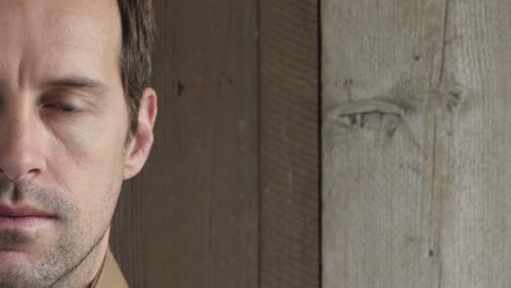 half face portrait of young attractive man looking at camera serious on wooden background copy space close up