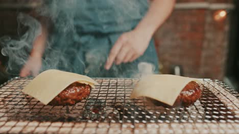 Chefs-adds-cheese-slices-on-top-of-burger-meat-patty,-whiling-grilling