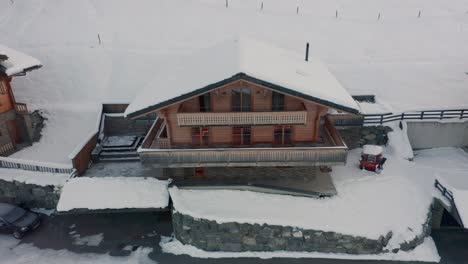 drone flying away from snow covered rooftop of luxurious chalet