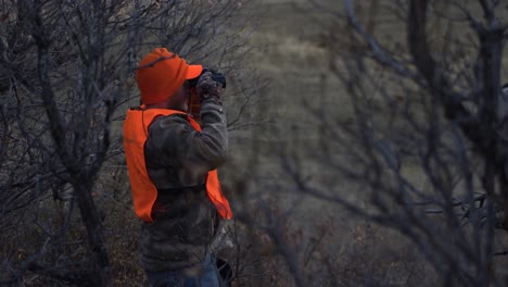 hunter stands and looks through binoculars