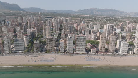 lateral drone shot of levante beach in benidorm, moving left to right with tall skyscrapers and clear skies