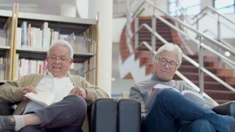 amigos mayores alegres sentados en sillones en la biblioteca