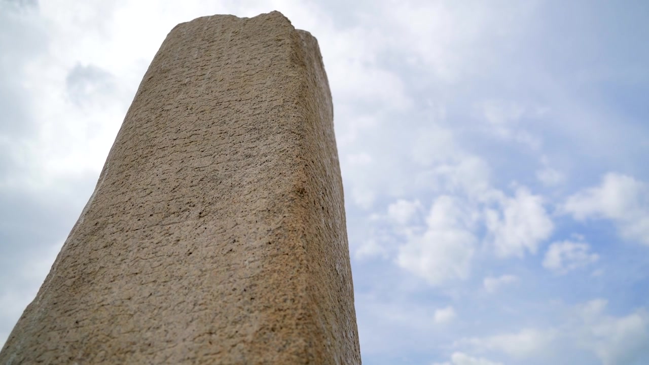 Antica colonna di pietra con iscrizioni contro un cielo nuvoloso