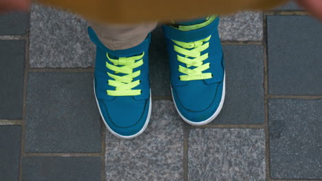 Child-feet-in-blue-trainers-on-sidewalk