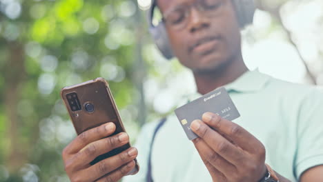 Typing,-phone-or-black-man-in-park-with-credit