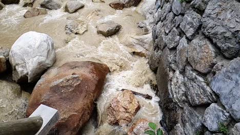 cámara lenta de un tronco atrapado detrás de una gran roca en medio de un río que se mueve rápidamente
