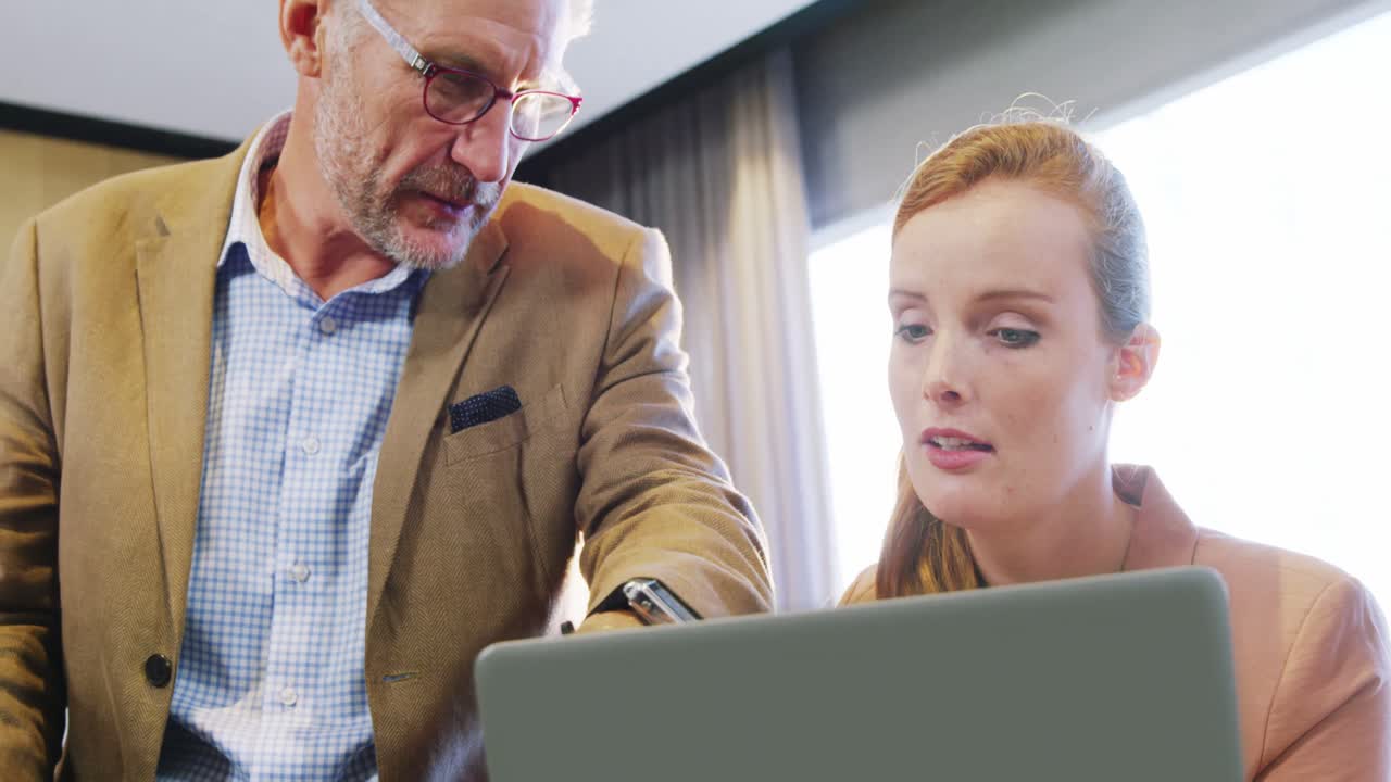 бизнесмен и коллеги обсуждают ноутбук за столом