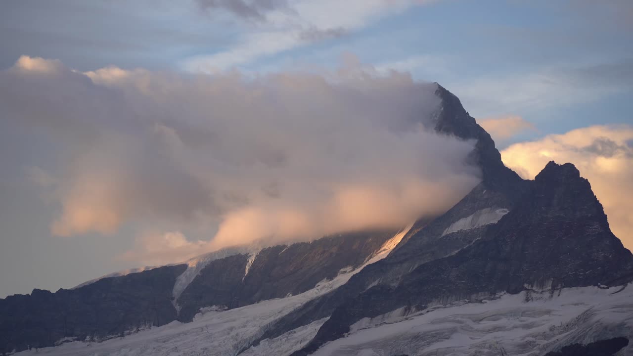 Soft golden sunrise light breaks through clouds, gently illuminating the rugged face of Kleines Schreckhorn in the Swiss Alps. Location: Bernese Alps, Switzerland (Schweiz).
