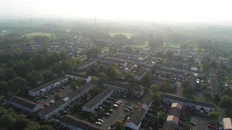 Aerial-view-looking-down-over-British-suburban-neighbourhood-town-buildings-at-golden-hour-pan-right