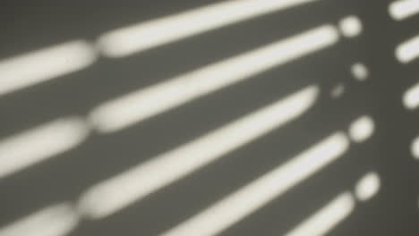 shadows on the wall of an electric window shutter being opened in room