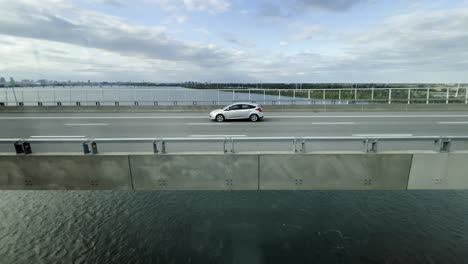 stunning view of a bridge spanning the saint lawrence river in montreal, captured from moving train. vehicles traverse structure as city skyline and calm waters enhance the scenic atmosphere, canada
