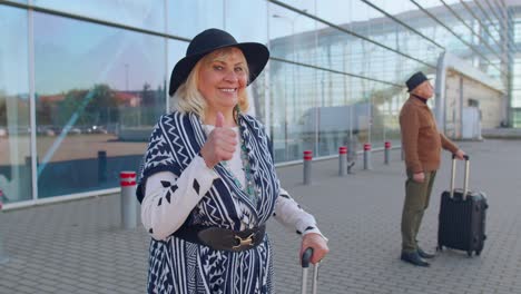 Senior-pensioner-tourist-grandmother-stay-near-airport-hall-celebrate-success-win-winner-gesture