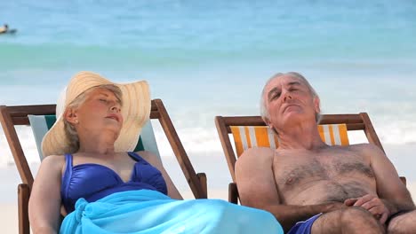 una pareja de ancianos relajándose en sillas de playa.