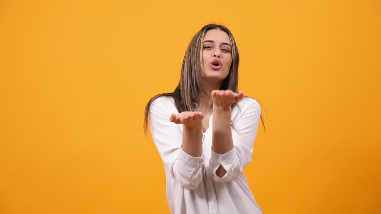 Woman blowing a kiss on yellow background