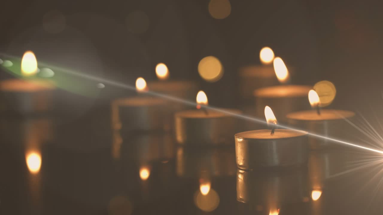 Narrow light beam sweeping over tealight candles, creating starburst flare enhancing candle glow