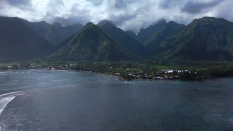 teahupoo tahiti new pedestrian bridge aerial drone view french polynesia bay coastline boats blue sky clouds wsl surfing summer olympic venue town village mountain peaks surfer wave reef forward up