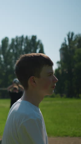 a young boy heads a soccer ball outdoors, while in the blurred background, another person is holding a ball up