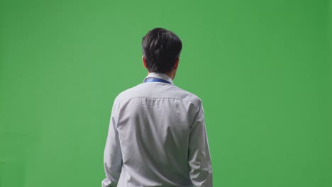 man in a light gray shirt and light blue tie, back view, green screen