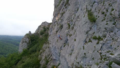 circular drone footage of a man stopped while lead climbing in the pyrenees moutains at tarascon sur ariège