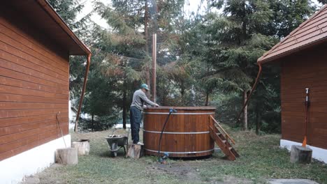 man alight the fire for traditional hot tub between the wooden houses