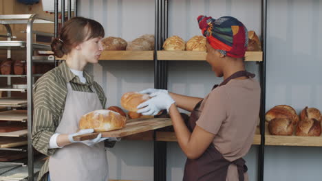 mujeres multiétnicas sonriendo y charlando durante el día de trabajo en la panadería