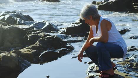 senior woman sitting on rock near side 4k