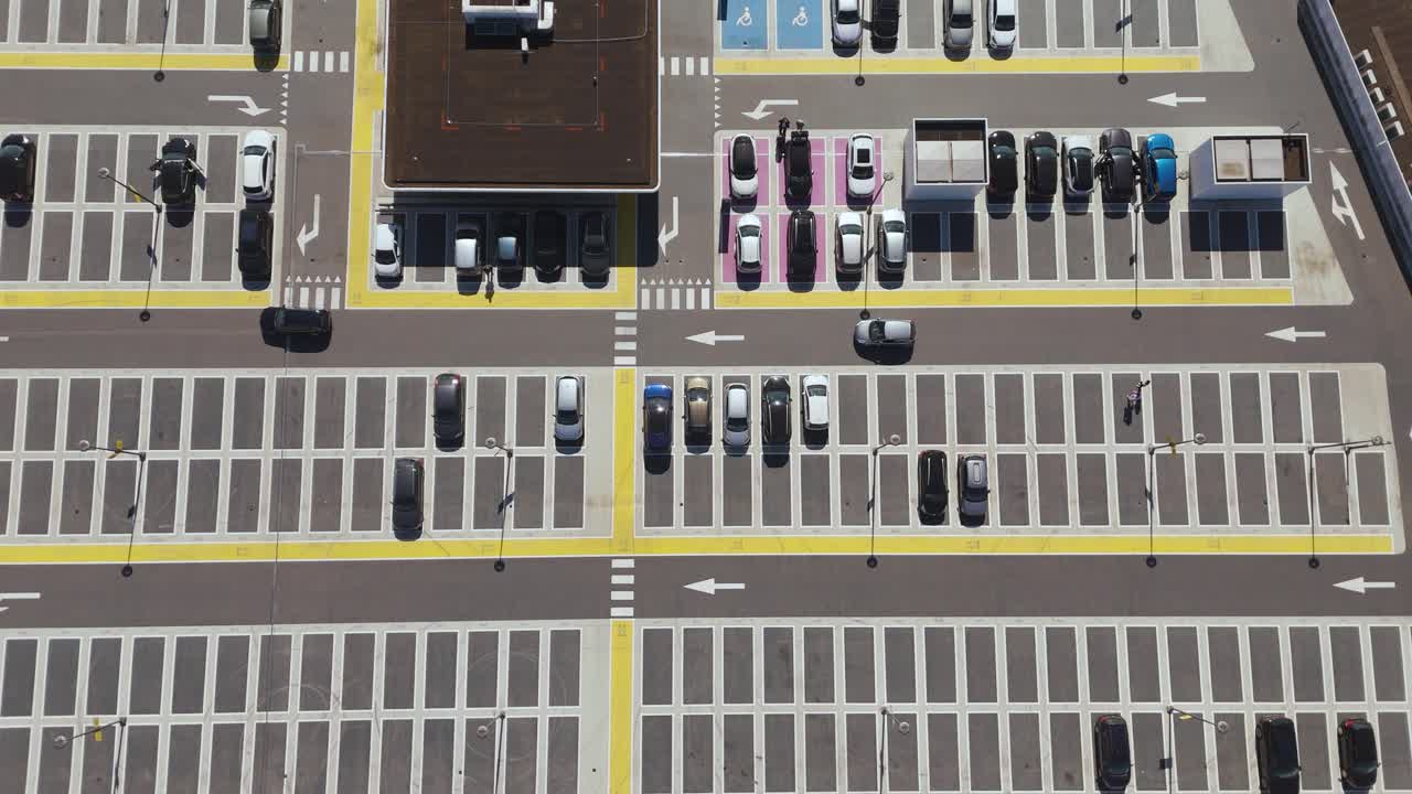 Aerial footage of a structured parking lot in the Netherlands. Captured directly from above, the image shows parked cars, directional arrows, parking bays and symmetry