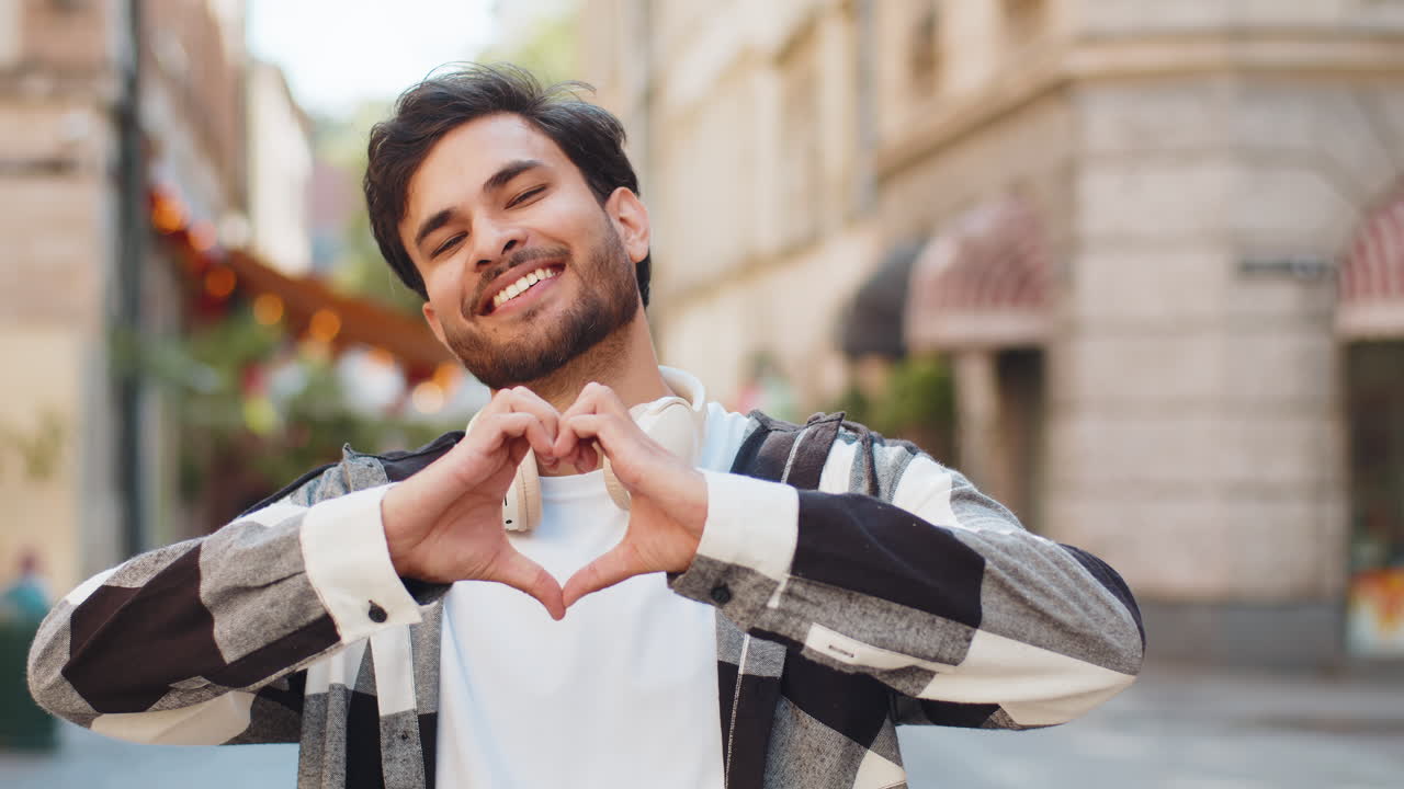 Indian man makes symbol of love showing heart sign to camera express romantic feelings on street