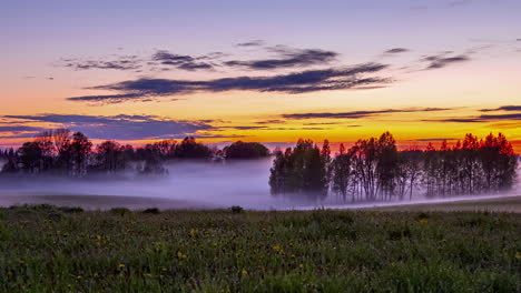 scenic vibrant sunset time lapse of mist flowing over farm land, vivid sky