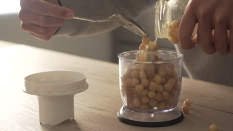 adding chickpeas to a blender for hummus