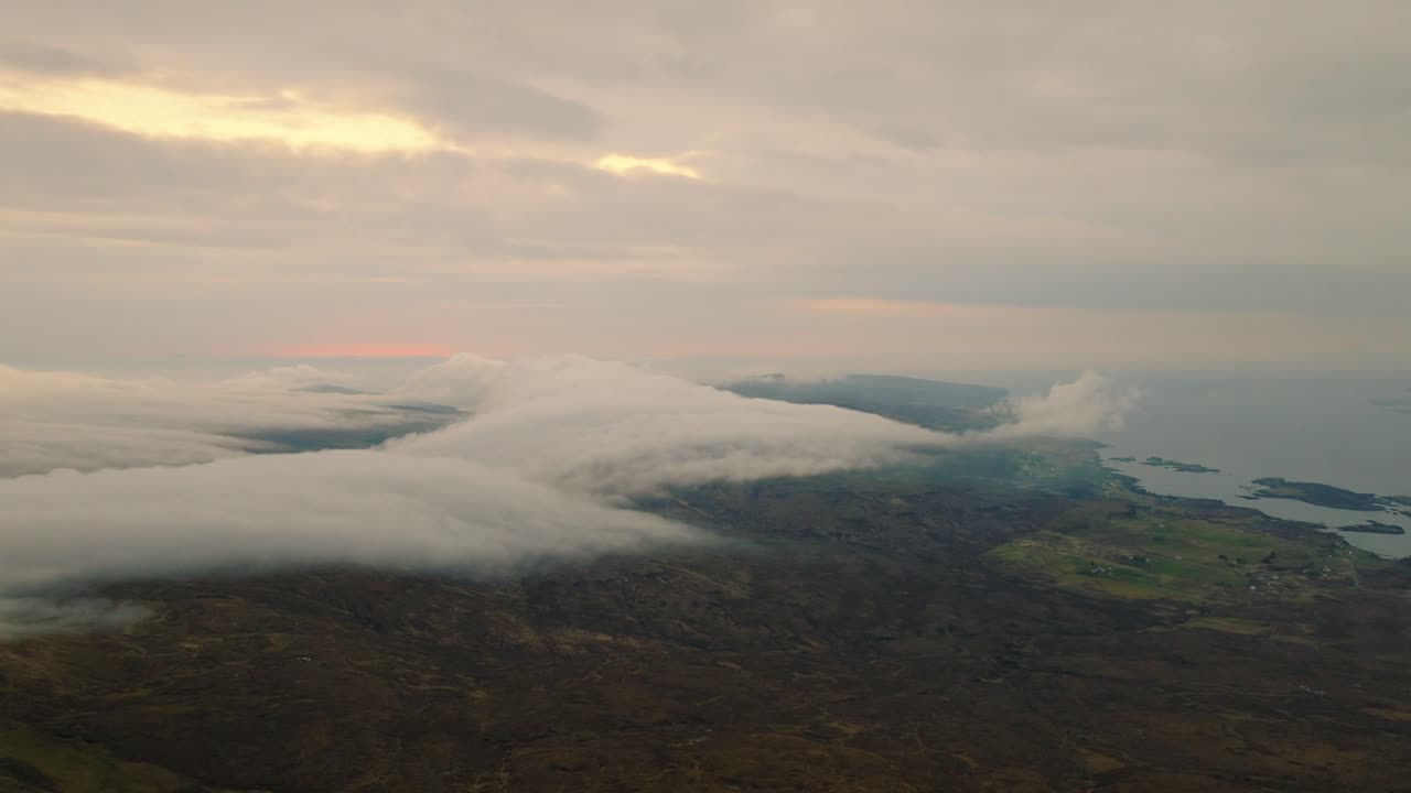 Aerial drone shot of the Scottish coastline after sunset, with dramatic clouds rolling over the landscape and fading light casting a moody, cinematic atmosphere