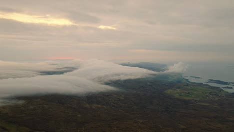 aerial drone shot of the scottish coastline after sunset, with dramatic clouds rolling over the landscape and fading light casting a moody, cinematic atmosphere