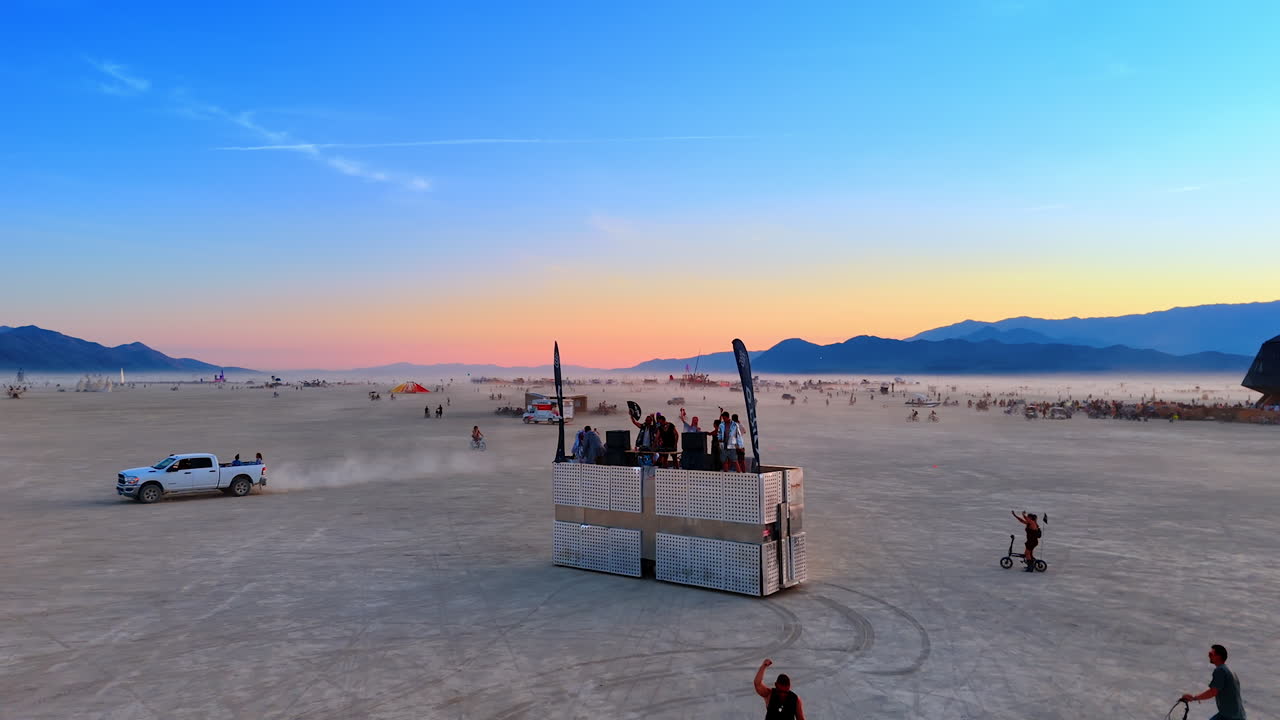 Nevada, USA, 22 August 2025: DJ booth at Burning Man with people dancing. DJ and group of people dancing near stage booth in the desert during Burning Man festival at dusk