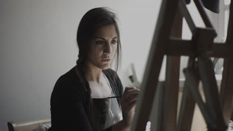 young woman artist paints on canvas in her studio