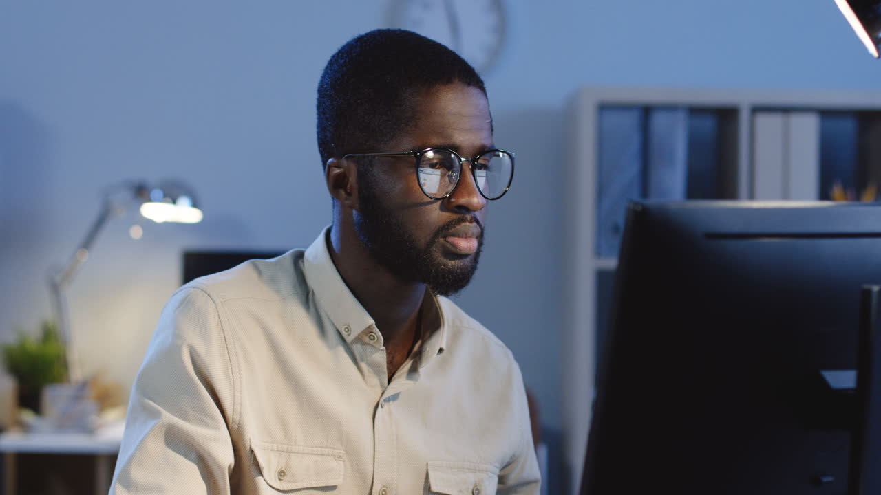Close Up View Of Young Tired Office Worker In Glasses Sitting In The Office In Front Of The Computer In The Office At Night