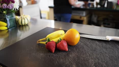 Frutas-Y-Un-Cuchillo-En-Una-Tabla-De-Cortar-Con-La-Cámara-Girando-Lentamente-En-Un-Restaurante