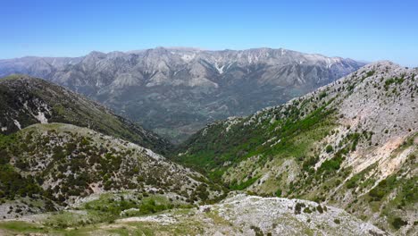 Aerial-view-of-rough-and-dry-mountainous-terrain-with-sunlight-and-blue-skies