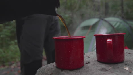 Llenando-Dos-Tazas-De-Café-Rojas-Para-Acampar