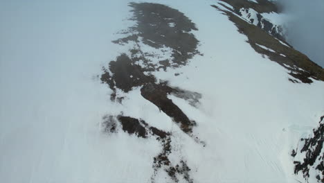 Orbit-shot-of-a-Hiker-standing-on-a-cloudy-mountain-top-during-midnight-sun-season