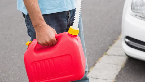 sección media de un hombre caucásico sosteniendo un bote de combustible de plástico rojo